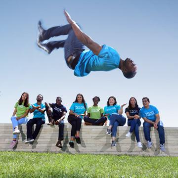 A student does a backflip while eight other students watch.